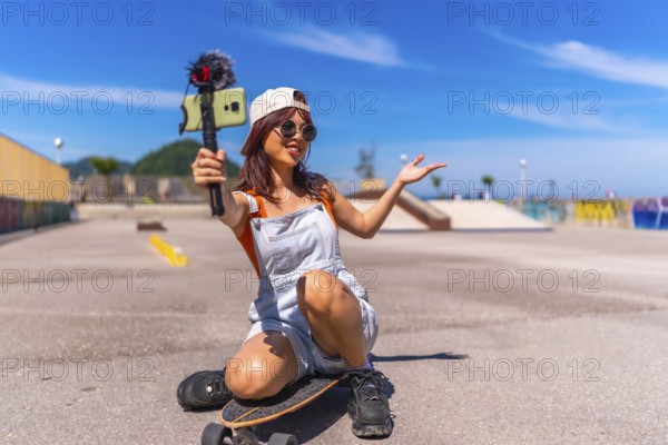 Chinese female young vlogger recording online video with mobile phone while skating in an urban park