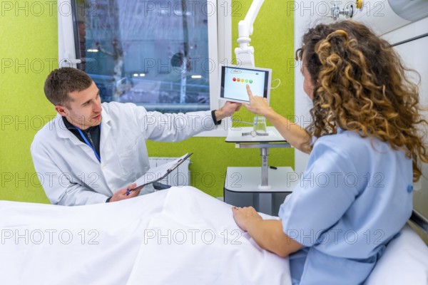 Doctor explaining results to a patient on hospital bed using hanging tablet on the room