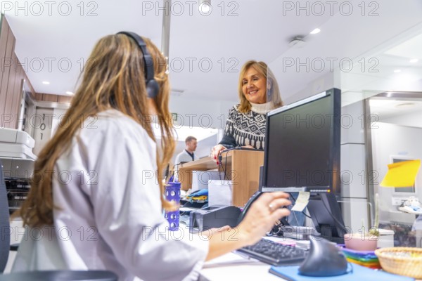 Receptionist of an hospital attending a mature woman standing in front the desk