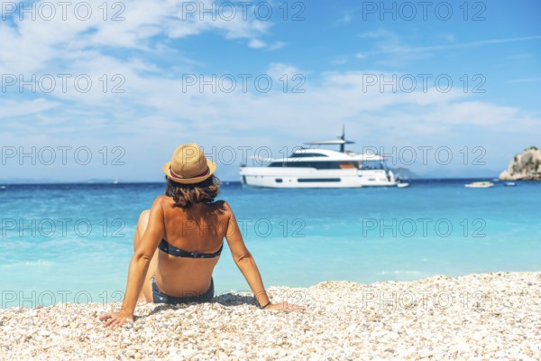 Portrait of a tourist woman sitting on Gidaki Beach on the island of Ithaki or Ithaca in the Ionian sea in the Mediterranean sea of Greece