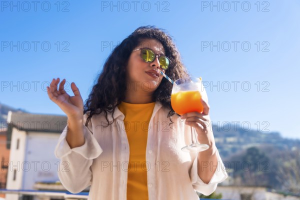 Cool woman sucking a cocktail with straw in a rooftop during a summer party