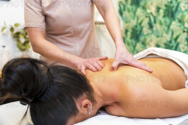 Close-up cropped photo of an unrecognizable masseur giving a back massage to a woman lying on stretcher