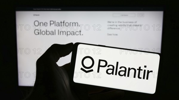 Stuttgart, Germany, 03-17-2023: Person holding cellphone with logo of US analytics company Palantir Technologies Inc. on screen in front of webpage. Focus on phone display, Europe