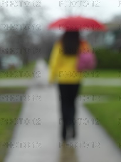 Young woman with an umbrella walking along the street on a rainy day