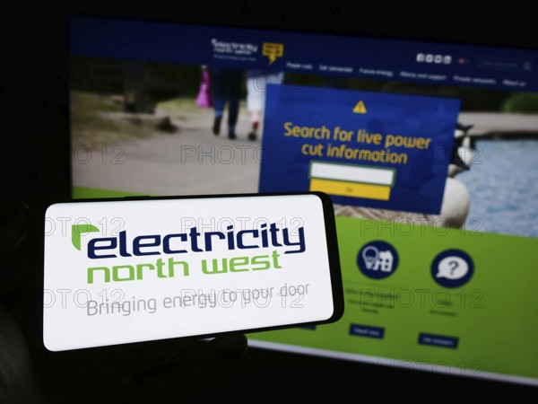 Stuttgart, Germany, 10-28-2023: Person holding mobile phone with logo of British energy company Electricity North West Limited in front of web page. Focus on phone display, Europe