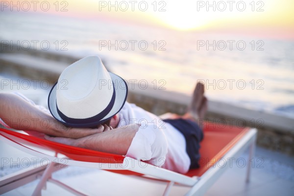 Young man relaxing on the beach back view. Summer vacation. Relax concept