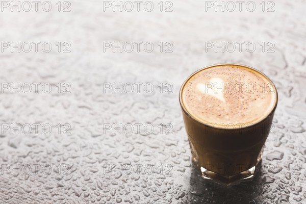 Hot latte with heart shape glass water drop surface