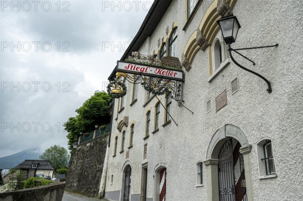 A traditional pub sign on a white wall of a European building on a cloudy day, Salzburg, Austria, Europe