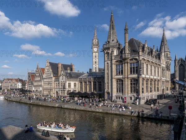 Medieval old town centre with historic buildings former post office building, St. Nicholas Church, Sint-Niklaaskerk and tourists in the tourist boat for the canal cruise on the river Leie, Ghent, East Flanders, Belgium, Europe