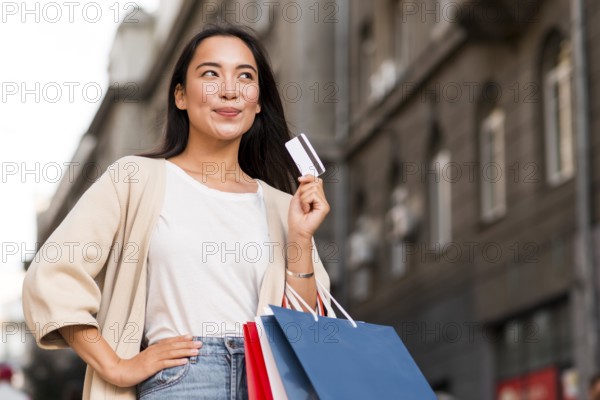 Happy woman outdoors holding shopping bags credit card