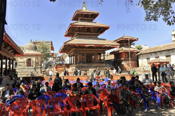 Group of people sitting on plastic chairs in front of a traditional temple, Kathmandu Valley, Kathmandu, Nepal, Asia