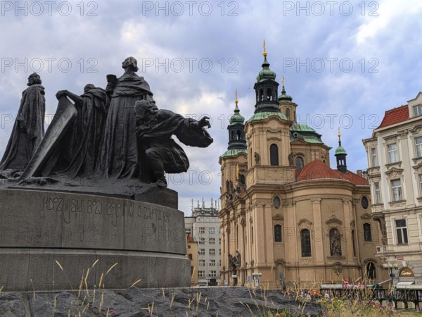 Statue and baroque church under a cloudy sky in a historic square, Gothic statue and a baroque church under a cloudy sky in a historical city setting. Prague, Czechia