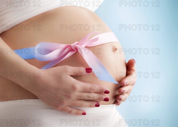 Pregnant pretty belly with colored ribbon. Third trimester