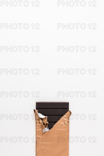 Dark chocolate bar golden wrapper white background