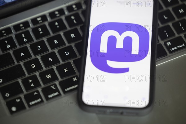 Logo of Mastodon, a new social networking service pictured here on a mobile phone above a keyboard of a computer