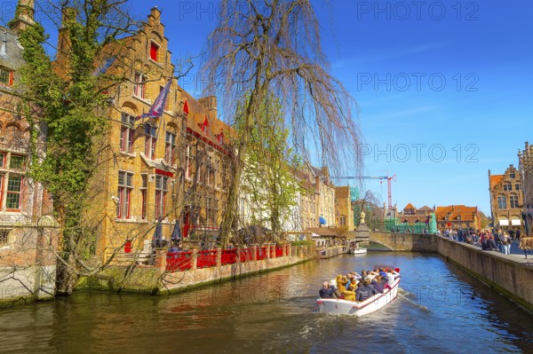 Bruges, Belgium, April 10, 2016: Scenic cityscape with medieval houses, boat with tourists and canal in Brugge, Europe