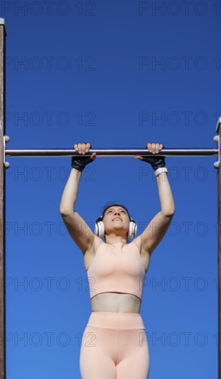 Young girl doing calisthenics exercise on bars outdoors. pull-up exercise