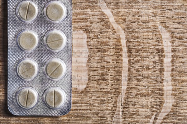 Blister pack with pills on vintage wooden board with organised copyspace medical concept
