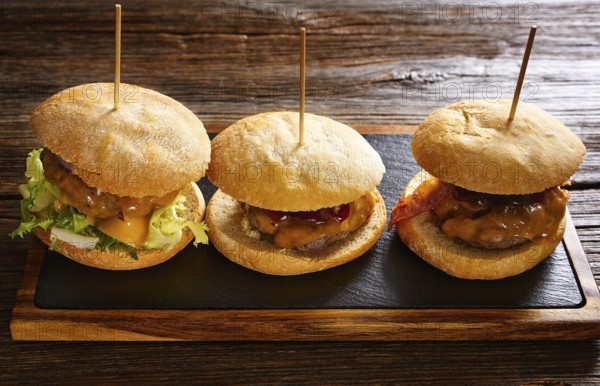 Burger in a row on a slate board and wood table