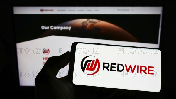 Stuttgart, Germany, 09-04-2022: Person holding mobile phone with logo of American aerospace company Redwire Corporation on screen in front of web page. Focus on phone display, Europe