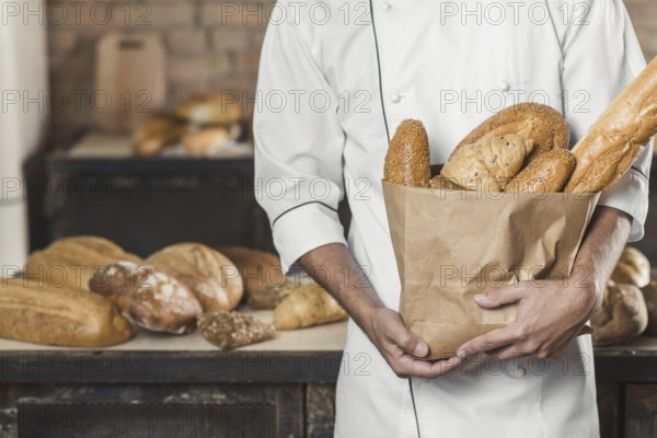 Mid section male baker holding paper bag with breads. Resolution and high quality beautiful photo