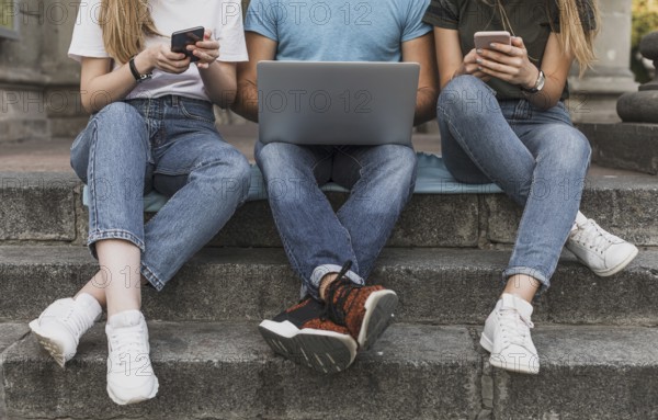 Teens sitting stairs working phones laptop. Resolution and high quality beautiful photo