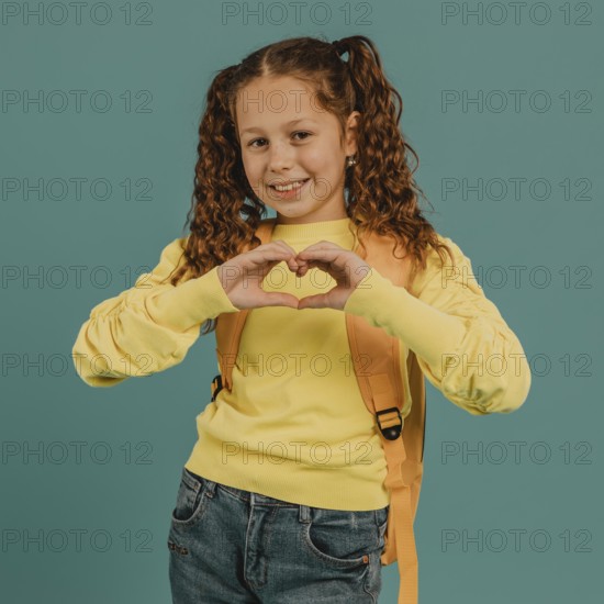 School girl with yellow shirt making heart shape