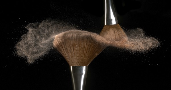 Make-up Brush spreading blush powder on black background