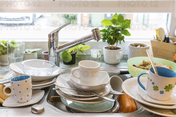 Messy kitchen counter with pile of dirty dishes in sink - Compulsive Hoarding Syndrome