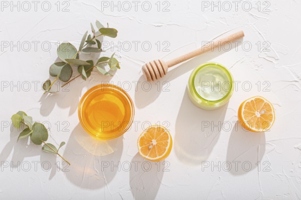 Natural organic ingredients for making cosmetic cream: avocado, honey, lemon and eucalyptus on white stone background, cosmetics and organic skin care for face and body care product, hard sun light