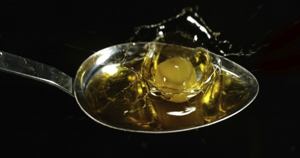 Green Olive, Olea europaea, Falling in a Spoon against Black Background