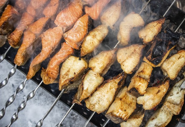 Fish kebab on skewers on the grill in winter. Salmon and halibut