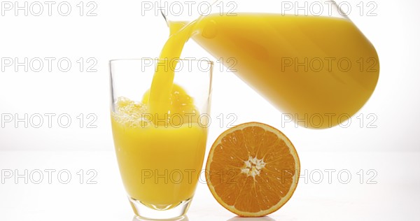 Orange Juice being poured into Glass against White Background