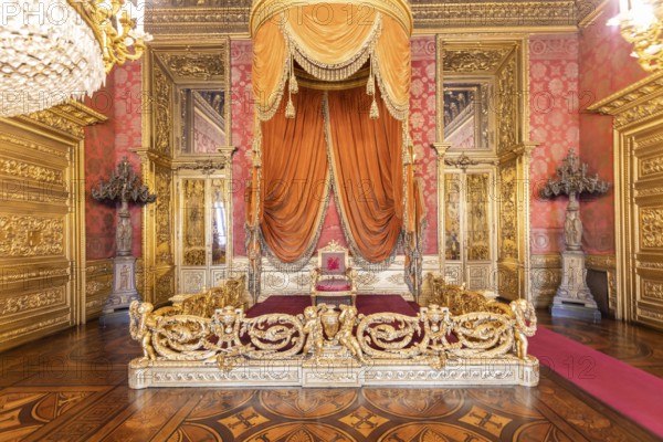Turin, Italy - Circa August 2021: old throne room interior with chair in luxury palace. Red and gold antique Baroque style - Savoia Royal Palace