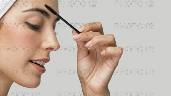 Sideways woman applying mascara her lashes