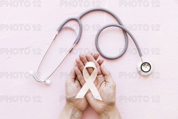 white awareness ribbon two hands with stethoscope pink background (1). Resolution and high quality beautiful photo