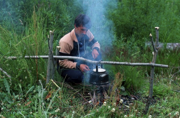 Man at campfire in taiga, Kamchatka, Russia, Europe