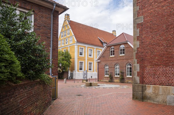 Idyllic alley with orange building and cobblestones between brick buildings, Lingen, Emsland, Lower Saxony