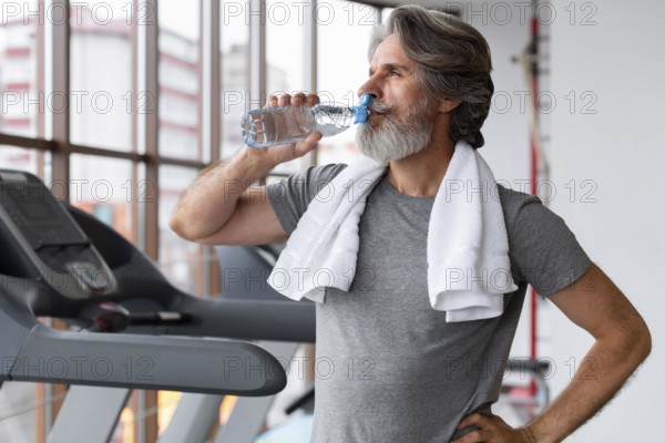 Medium shot man drinking water gym