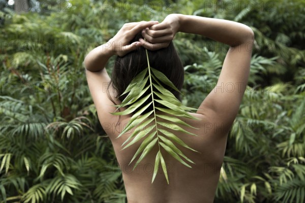 Back view woman posing with leaf