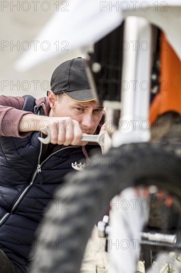 Portrait man trying fix motorbike