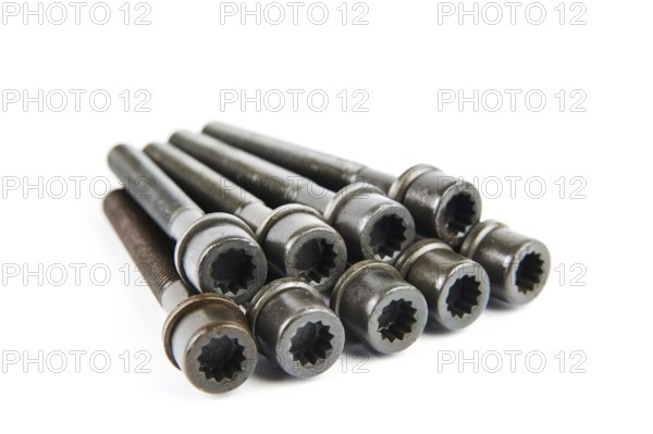 A set of new cylinder head bolts in oil on a white isolated background are shot in perspective at a wide angle. Spare parts for car repair