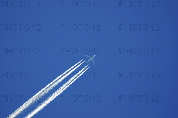 Four-engine jet with condensation trails in the blue sky