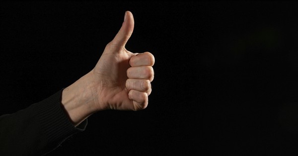 Hand of Woman making Sign against Black Background