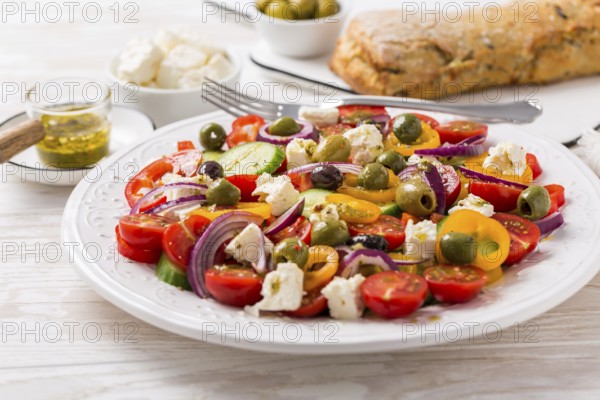 Greek salad of fresh cucumber, tomato, sweet pepper, lettuce, red onion, feta cheese and olives with olive oil dressing. Healthy food