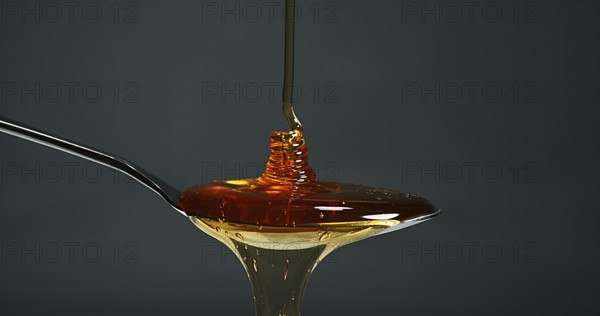 Honey Flowing in a spoon against Black Background