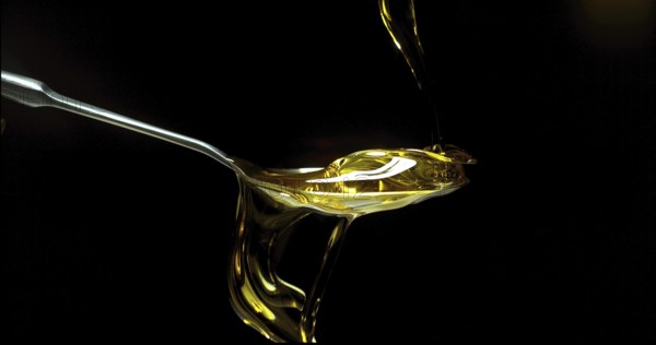 Olive Oil, Falling in a Spoon against Black Background