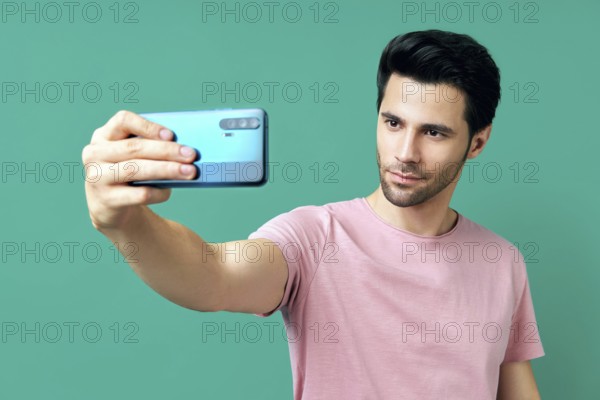 Portrait of handsome man taking selfie over blue background