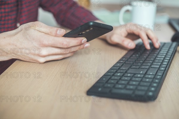 Young man is holding mobile phone in his hands, indoor at home office