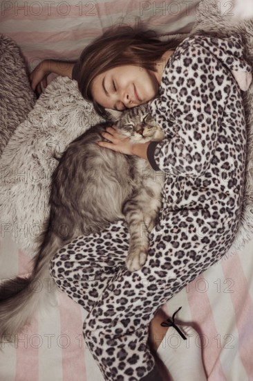 Girl pajamas hugging her cat laying bed
